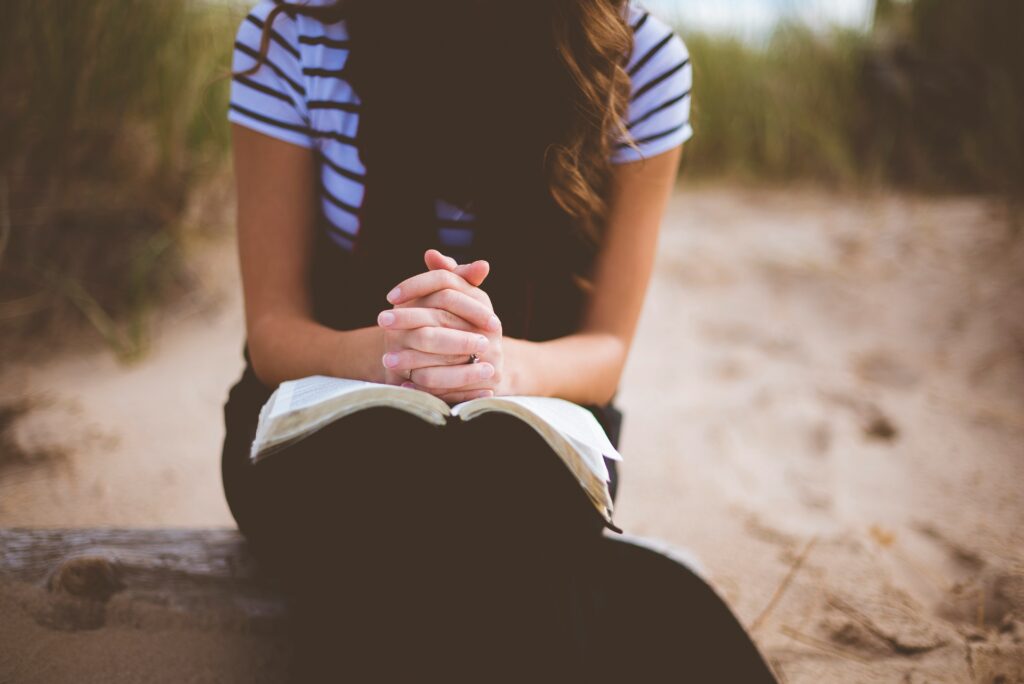 Woman with folded hands over her Bible